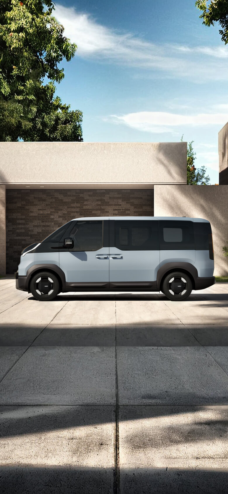 Vooraanzicht van de Kia PV5 Passenger rijdend langs de kust in een stedelijke omgeving