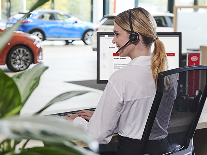  Kia-serviceadviseur zittend aan Kia-servicebalie