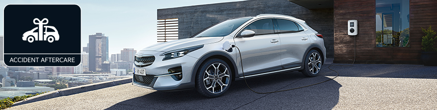 Kia electric vehicle charging via a home charging point, with 'Kia Accident Aftercare' stamp